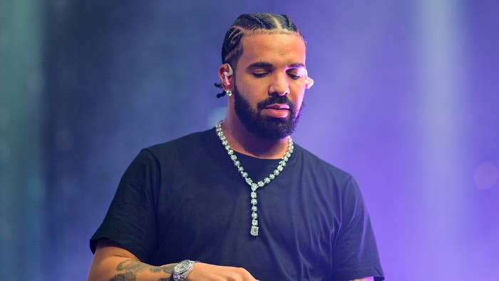 Drake, wearing a black t-shirt and a large diamond necklace, performs on stage