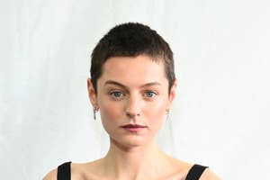 Person with short hair and earrings poses for a headshot against a plain background