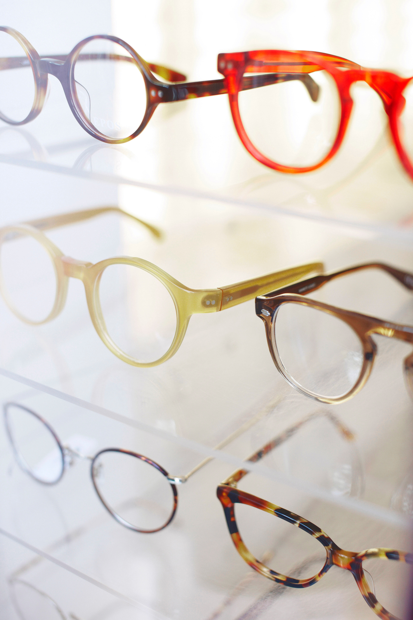 A display showcasing a variety of eyeglasses with round and rectangular frames, neatly arranged on transparent shelves