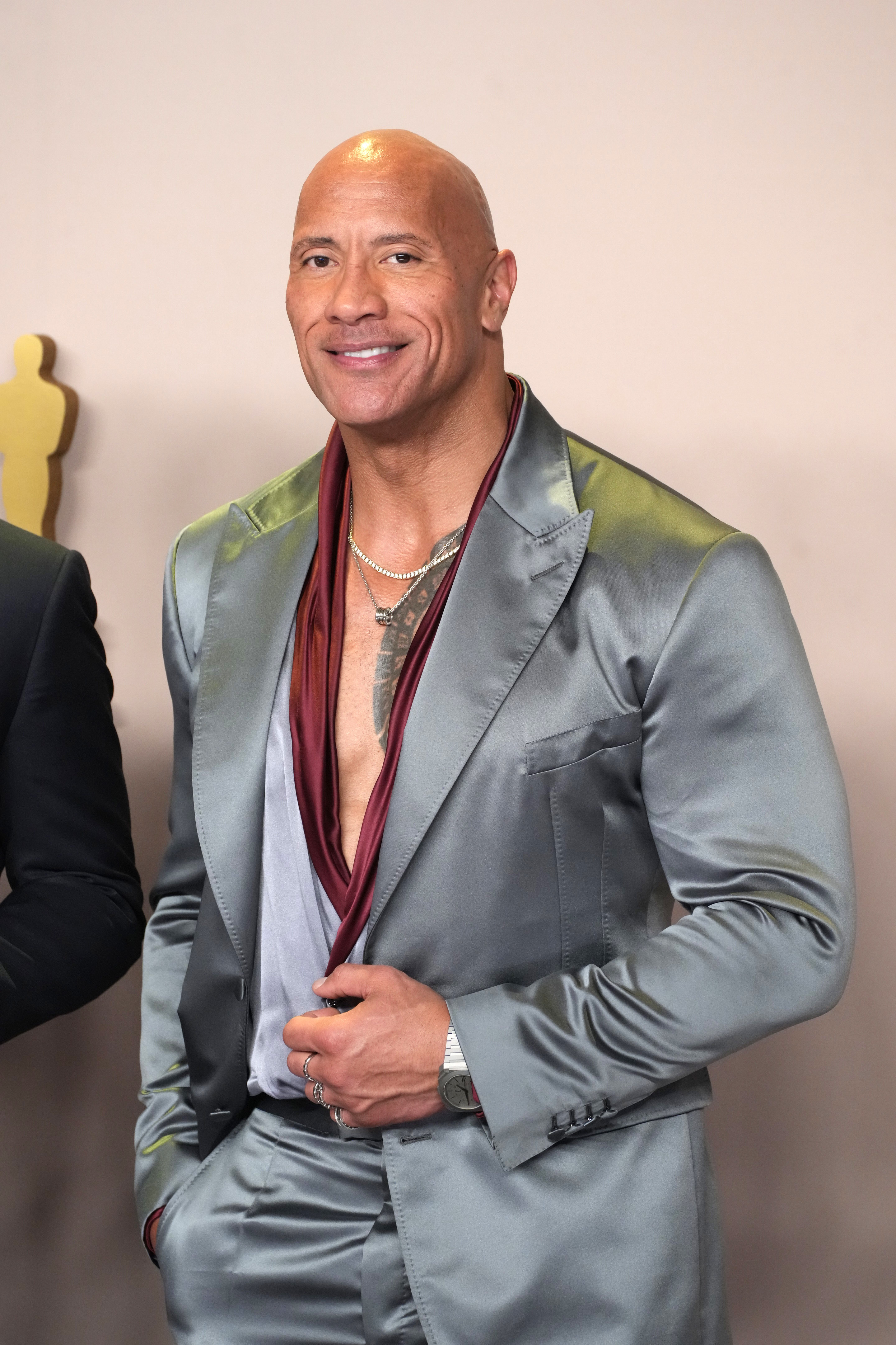 Dwayne Johnson in a satin suit with an open-collar shirt and visible necklace, posing at an event