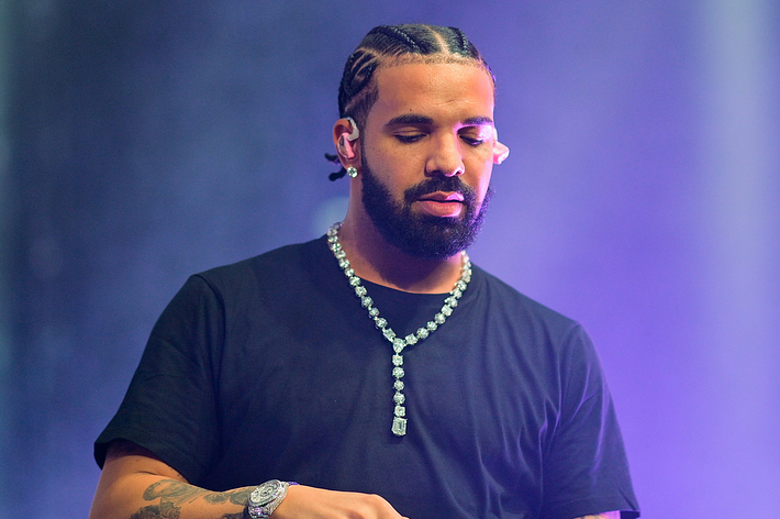 Drake, wearing a black t-shirt and a large diamond necklace, performs on stage