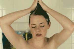 Woman in a shower with hands on her head, eyes closed, looks relaxed