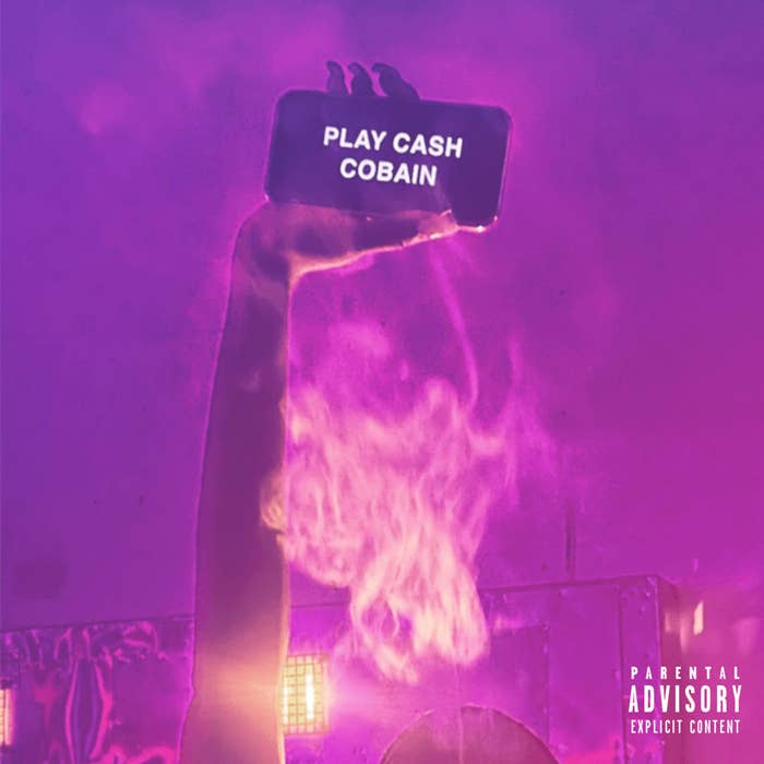 A hand holds a phone with the text &quot;PLAY CASH COBAIN&quot; against a smoky background. The image includes a &quot;Parental Advisory Explicit Content&quot; label