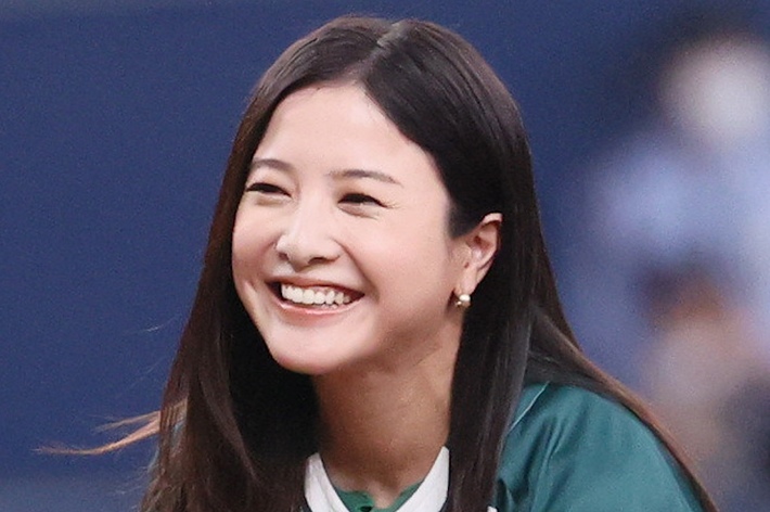 女性が野球のユニフォームを着て微笑んでいる。