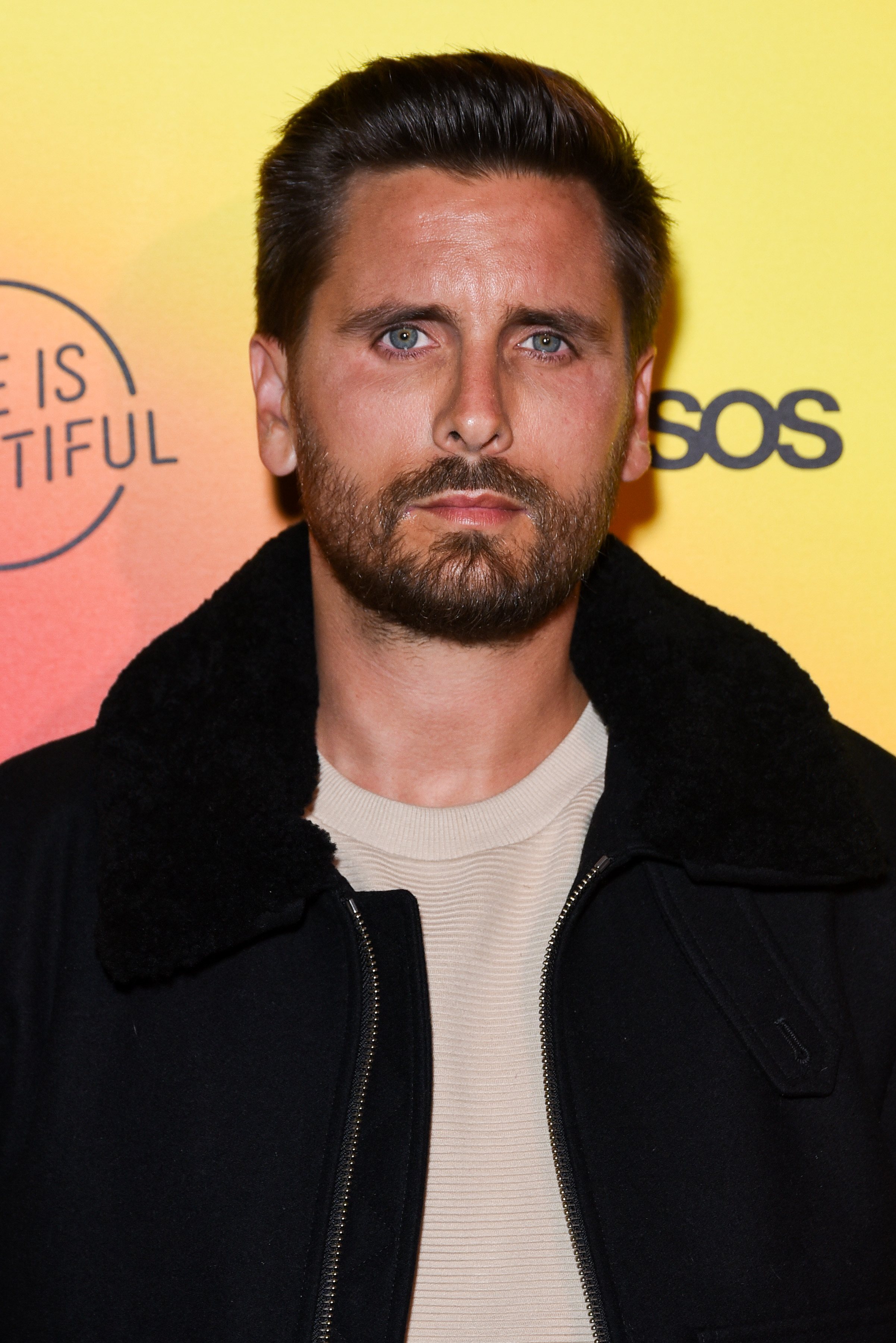 Scott Disick at a "Life is Beautiful" event, wearing a casual black jacket over a beige shirt