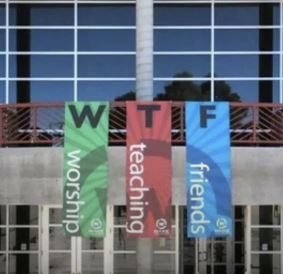 Banners hung in front of a building display the letters "WTF" vertically. Underneath each letter, the words read: "worship," "teaching," and "friends."