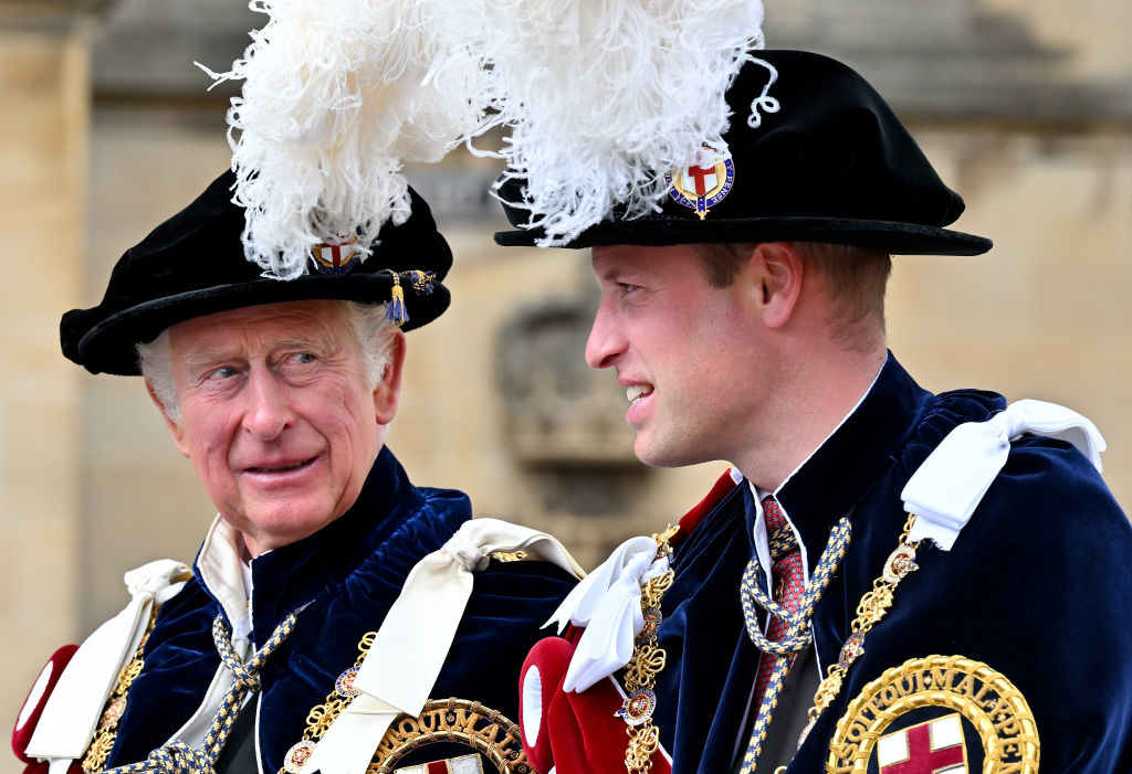 King Charles III and Prince William wear traditional formal regalia with feathered hats, attending a ceremonial event