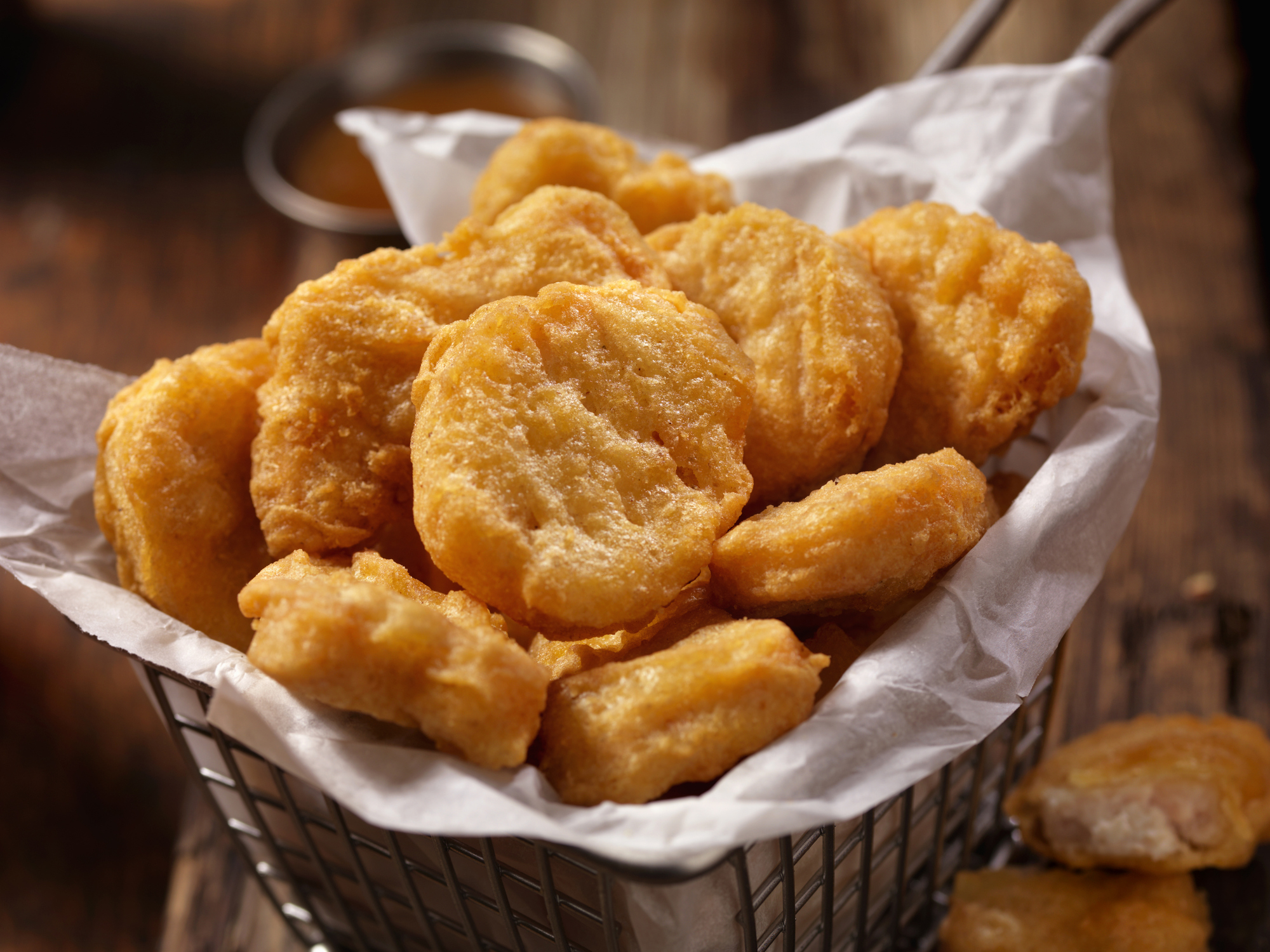 En kurv fylt med sprø, gylne kyllingnuggets på et trebord