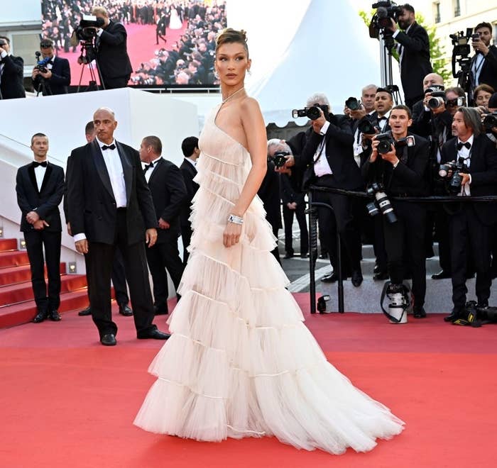 Bella Hadid on the red carpet in a tiered, ruffled gown, surrounded by photographers and onlookers