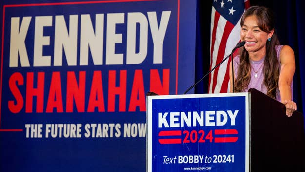 Lawyer and political commentator, Kennedy Shanahan, speaks at a campaign event, standing at a podium with a "Kennedy 2024" sign