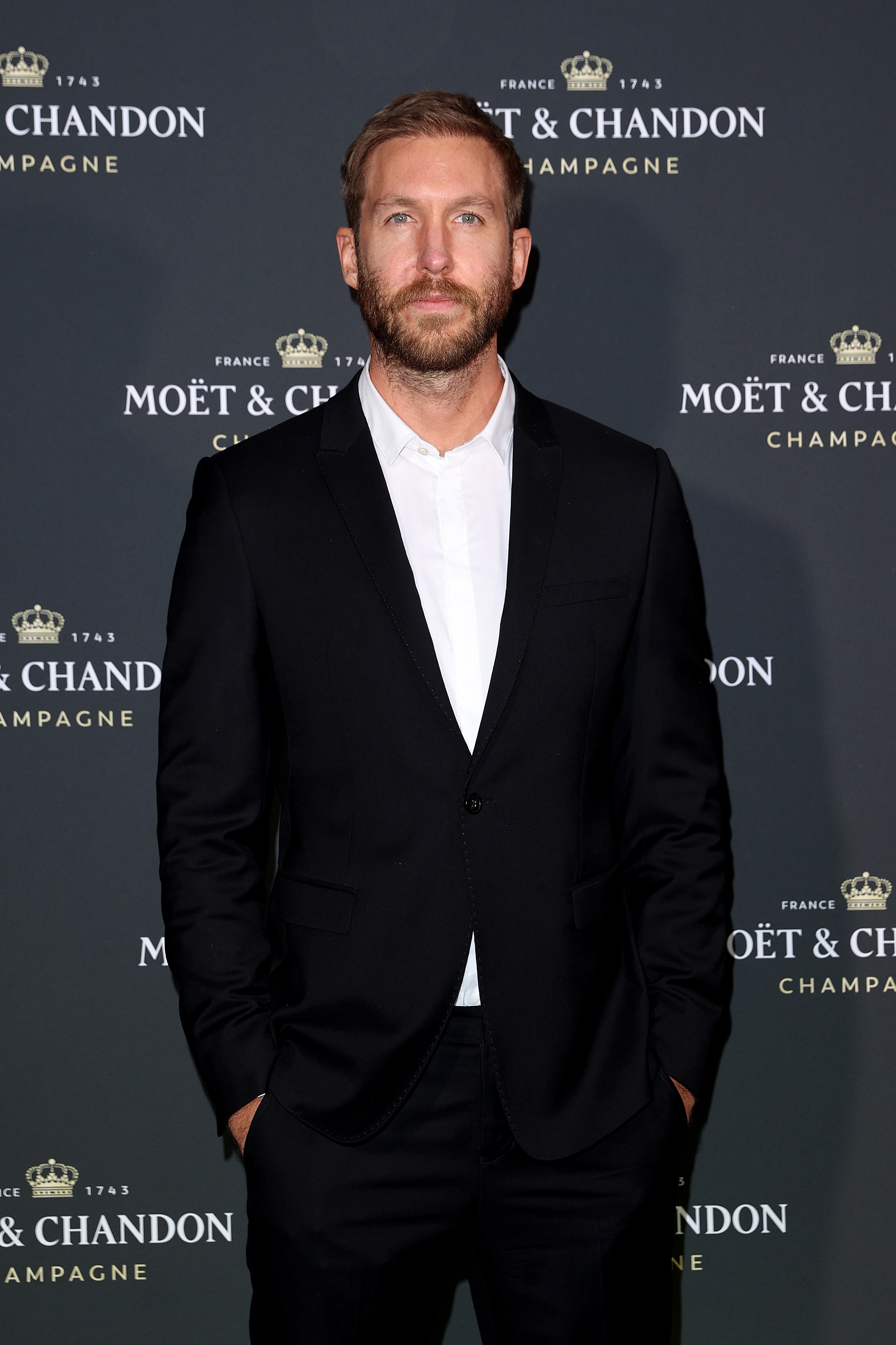 Calvin Harris attends a Moët & Chandon Champagne event, wearing a black suit with a white dress shirt