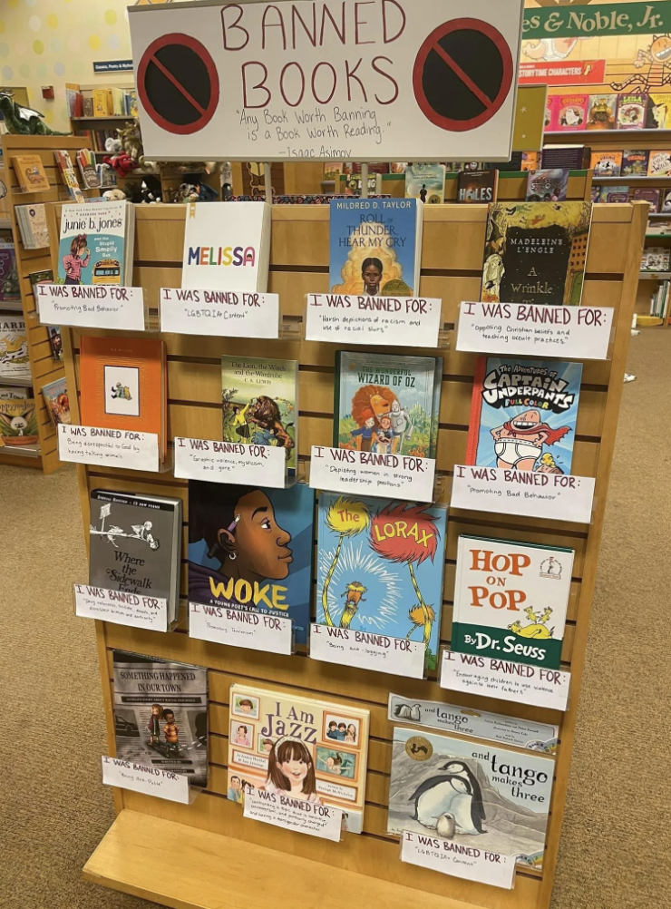 Books display with a sign &quot;Banned Books: Any Book Worth Banning is a Book Worth Reading.&quot; It includes titles like &quot;Melissa,&quot; &quot;Woke,&quot; and &quot;I Am Jazz&quot; with reasons for banning