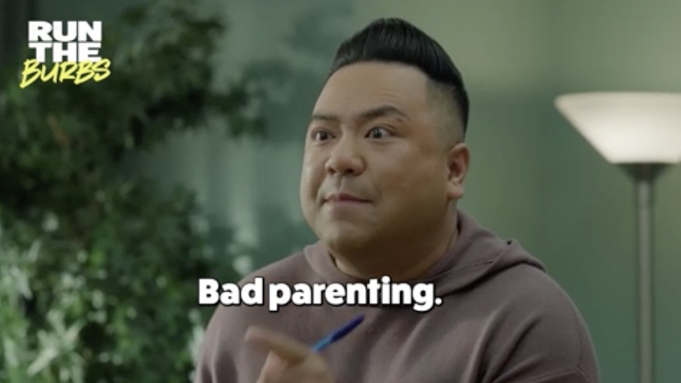 Image of actor Andrew Phung on "Run The Burbs," holding a pen, with the text "Bad parenting." in white letters