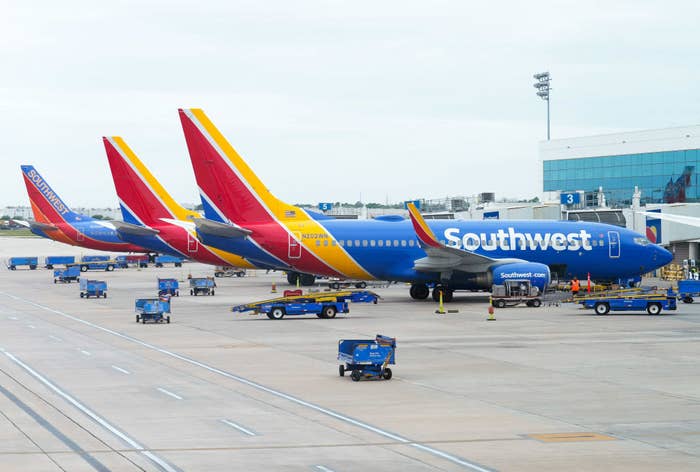 Four Southwest Airlines planes parked at airport gates, with baggage carts and workers nearby