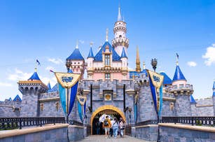 People entering the iconic Sleeping Beauty Castle at Disneyland, a popular travel destination