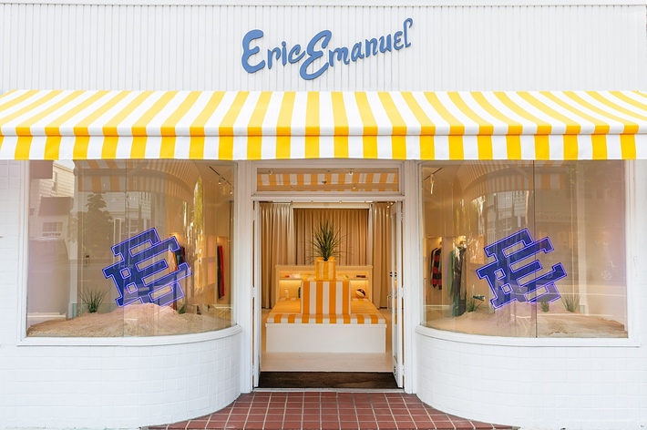Storefront of Erie Emanuel with yellow-and-white striped awning, featuring matching striped furniture inside under neon EE logos in the windows