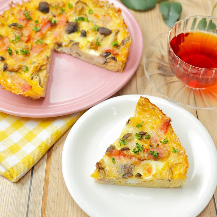 キッシュのホールから切り取った一切れが白い皿に載っている。隣に小さなガラスのカップに入った紅茶。