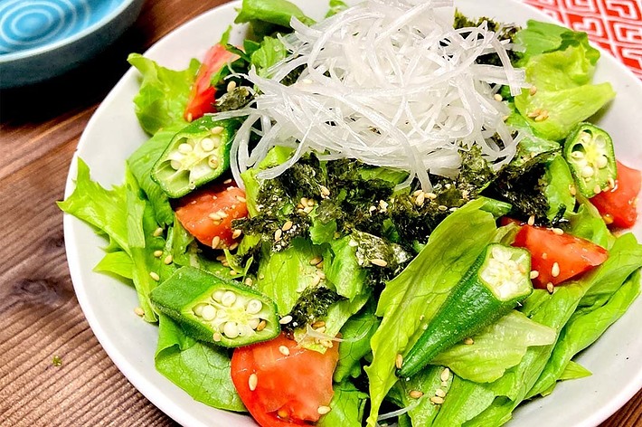 野菜の彩り豊かなサラダ。レタス、トマト、オクラがたっぷりと盛られ、大根の千切りと海苔がトッピングされています。