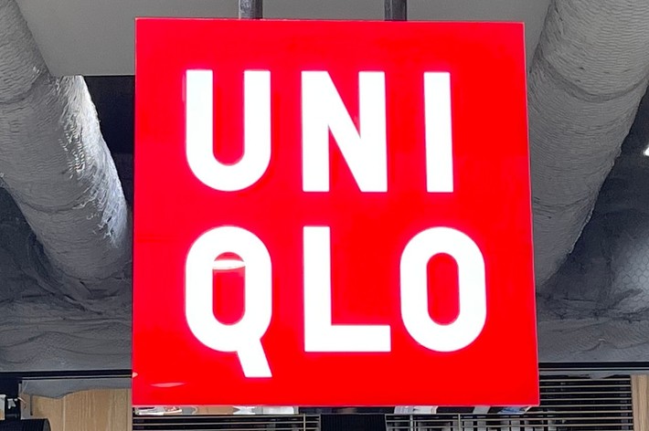 UNIQLO store sign hanging from the ceiling with clothing displays in the background
