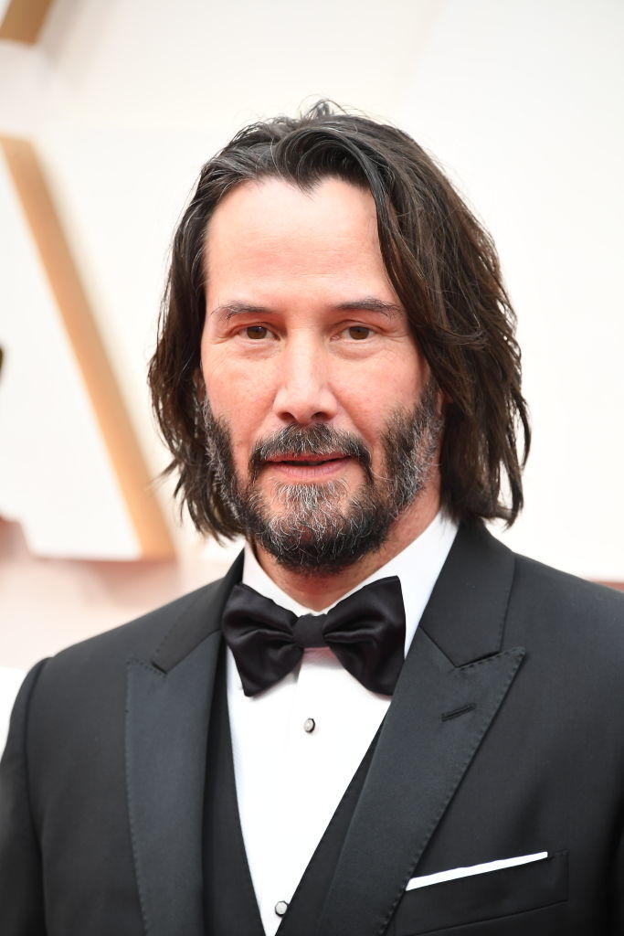 Keanu Reeves on the red carpet in a black tuxedo with a bow tie