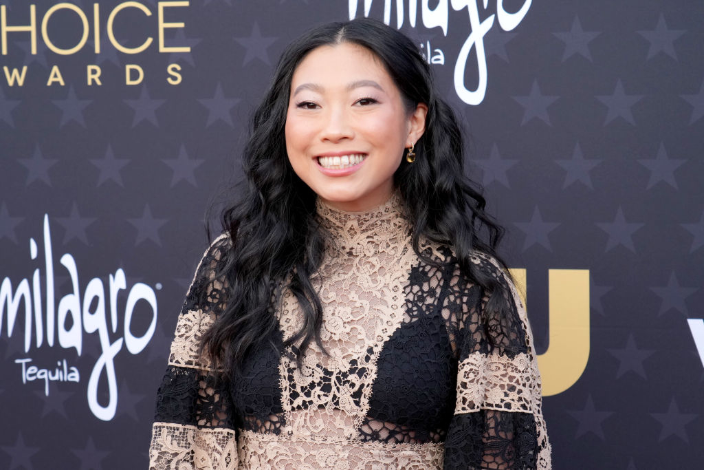 Awkwafina smiles on the red carpet at the Critics' Choice Awards, wearing a black and lace outfit