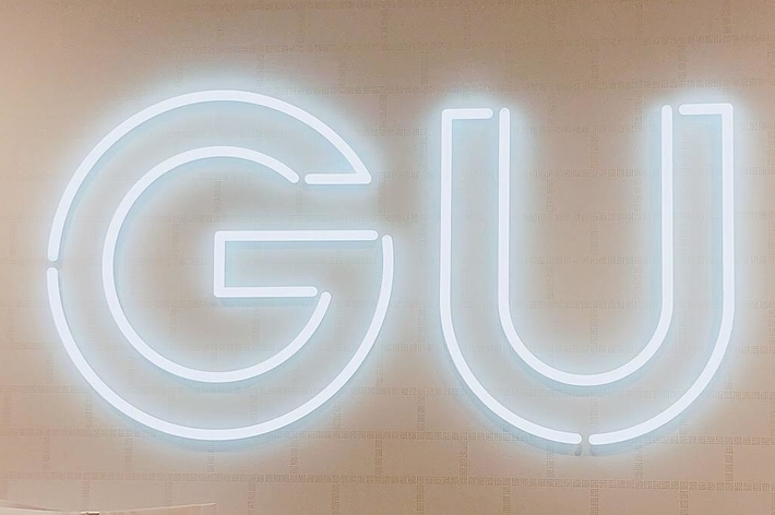 Gift-wrapped GU shopping bags displayed under a glowing GU sign in a store