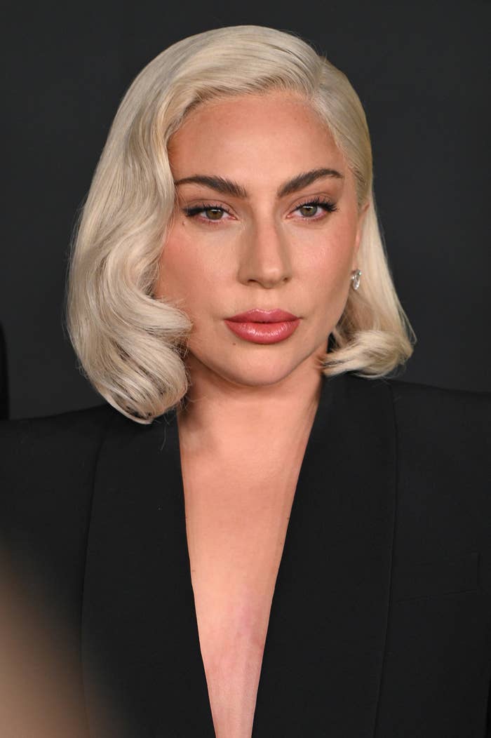 Lady Gaga in a classic Hollywood-glam look with a sleek, side-parted bob and dressed in an elegant, black blazer with a deep neckline