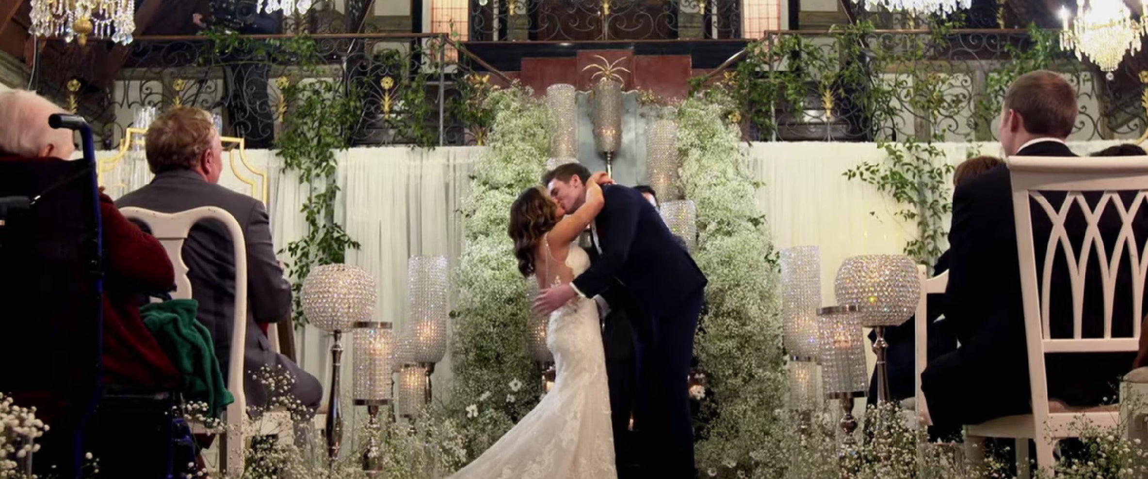 Cameron and Clare are getting married at the altar on "Married at First Sight." They kiss passionately in front of a decorated, indoor wedding venue