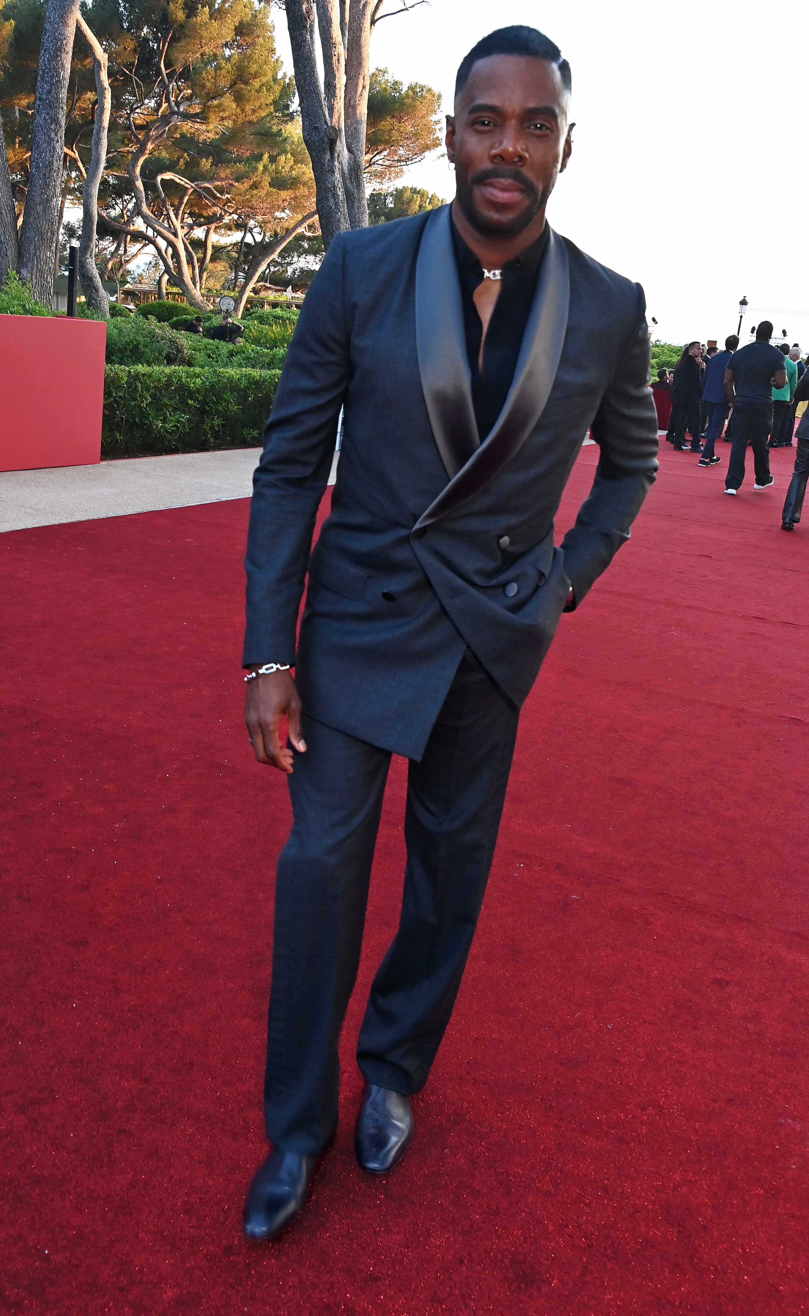 Colman Domingo on a red carpet, wearing a stylish dark suit with a satin lapel and black dress shoes
