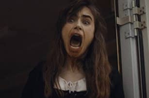 Young woman screaming with mouth wide open and eyes wide, looking frightened. Dark hair and wearing a black and white outfit