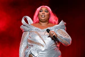Lizzo performs on stage wearing a shimmering silver outfit with intricate designs and holds a microphone