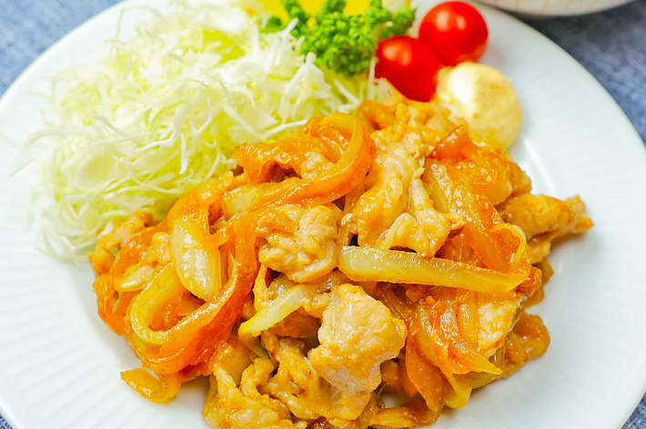 野菜と鶏肉の炒め物が盛られたお皿、横には千切りキャベツ、プチトマト、パセリとご飯の入ったおわんが置かれています。