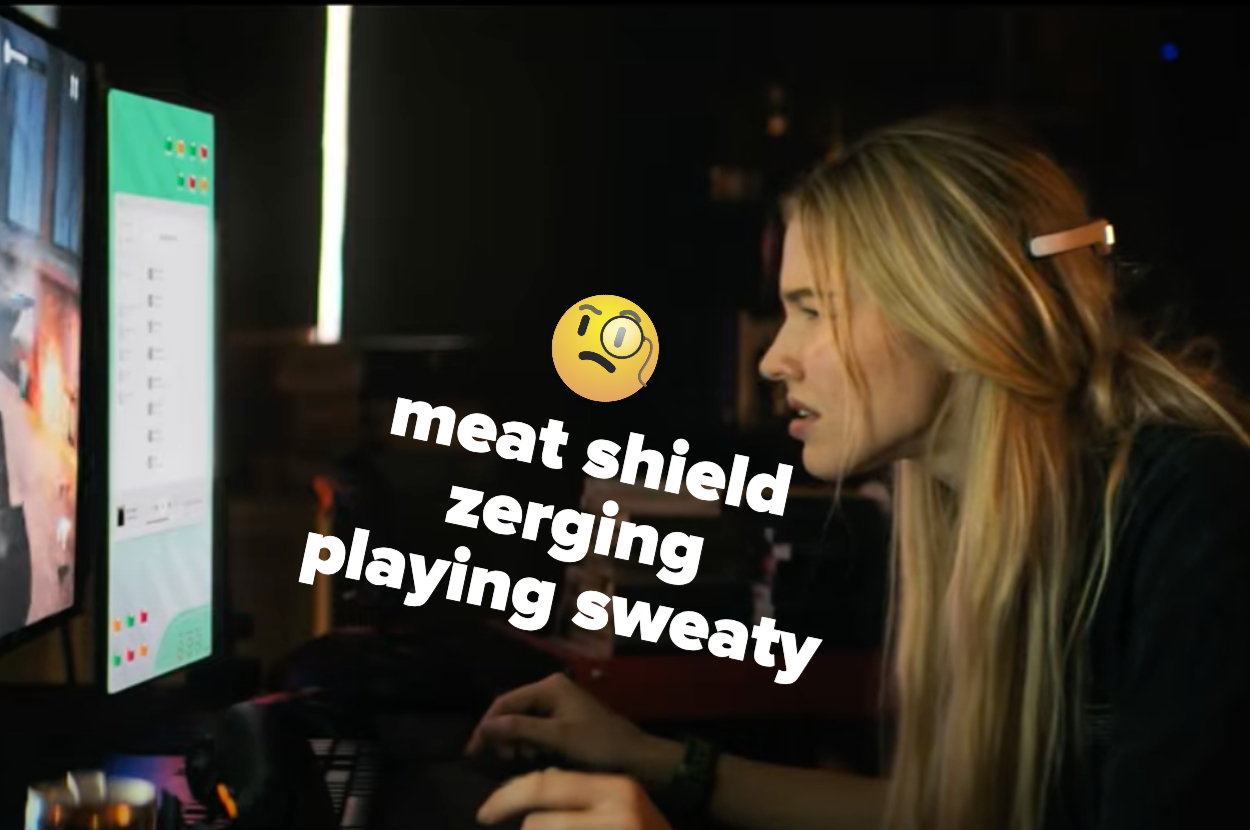 A person with long hair intensely focuses on a computer screen while playing a video game. The screen displays a game, and the overlaid text reads: "meat shield, zerging, playing sweaty."