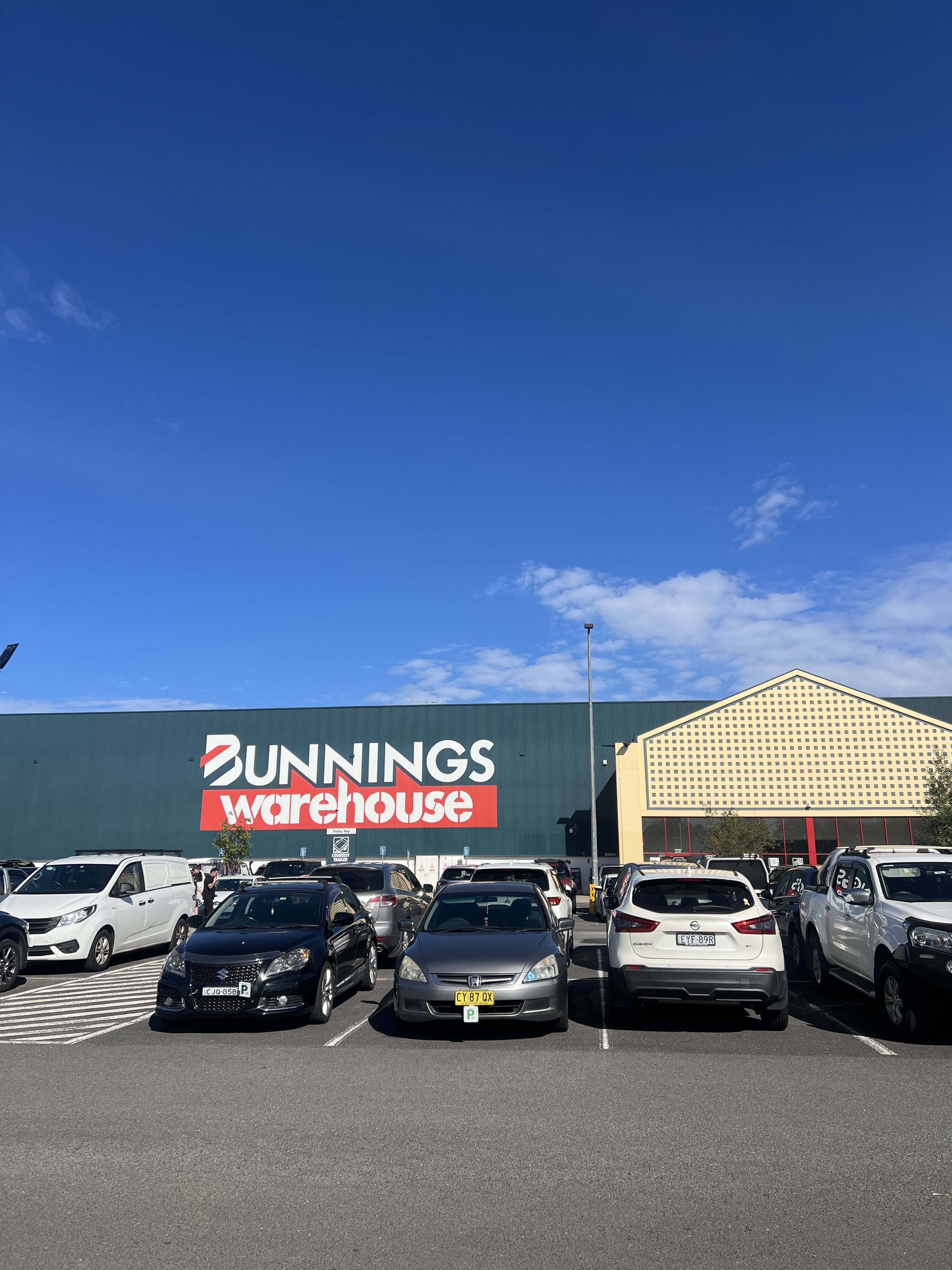 Exterior view of a Bunnings Warehouse with several cars parked in front