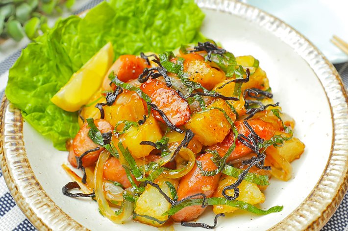 美味しそうな野菜と魚の和風炒めが白い皿に盛られている。レタスとレモン添え。