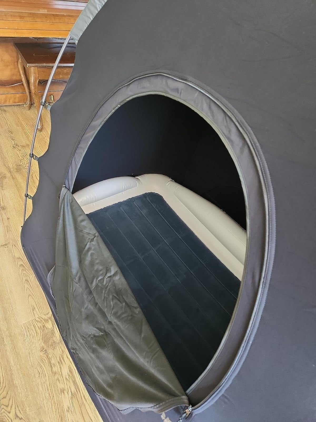 Tent with a zippered opening   revealing an inflatable furniture  inside, acceptable   up   successful  a country   with woody  flooring