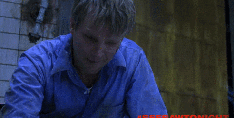 A bloodied man looks at a cellphone
