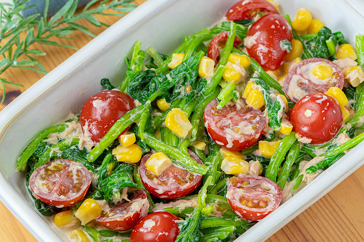 グラタン皿に盛られたトマト、コーン、ホウレンソウ、ツナを使ったクリーミーなサラダ。