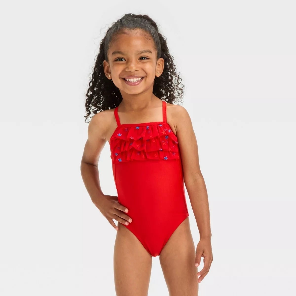 Gadis muda tersenyum dalam pakaian renang one-piece dengan detail acak-acakan, berpose percaya diri di depan kamera