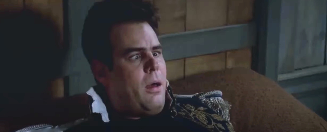 Dan Aykroyd in a scene from the movie &quot;Trading Places,&quot; looking surprised and lying on a bed in formal attire