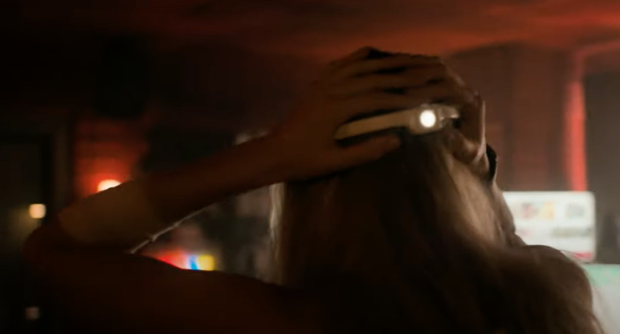 Rear view of a person with long hair adjusting VR headset in a dimly lit room