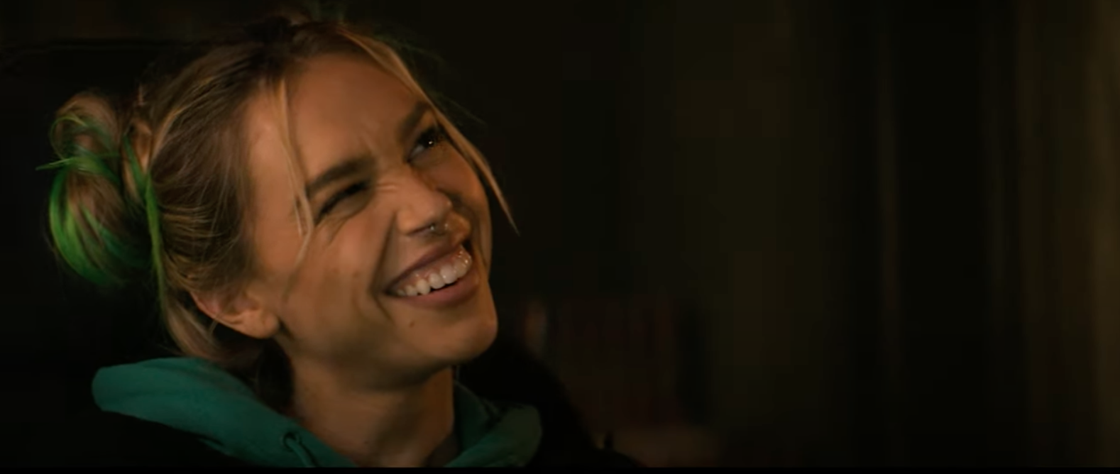 Alexis Ren smiling up at someone, wearing a hoodie with their hair styled in two buns
