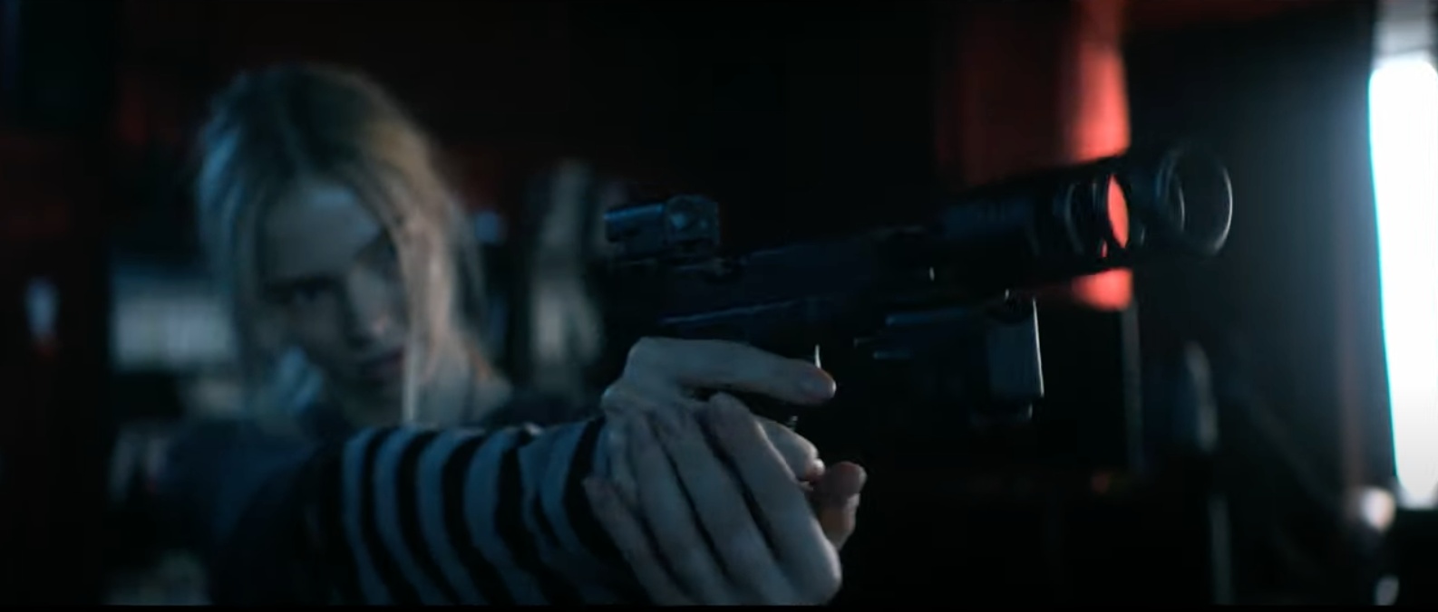 Sasha Luss in a striped shirt aiming a sniper rifle