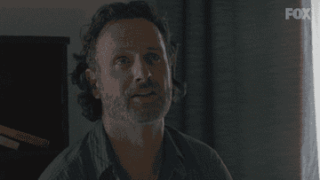 Man with a beard and short hair, wearing a blue shirt, sits indoors talking and gesturing. The scene is from a FOX TV show