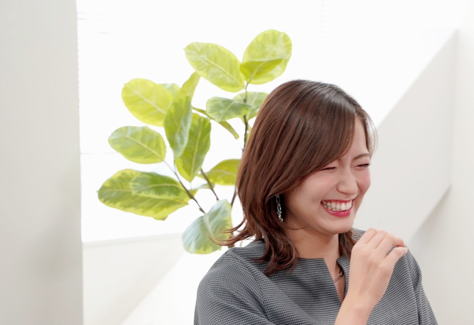 女性が笑顔で話している後ろに観葉植物が見える。