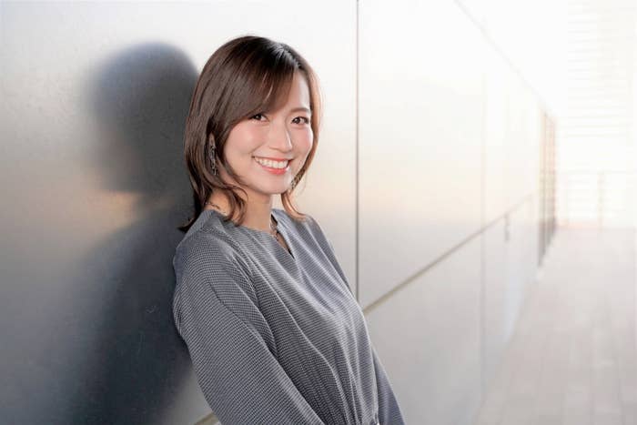 女性が廊下に立って微笑んでいる写真。