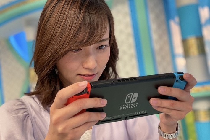 若い女性がNintendo Switchを持ってゲームをしている。