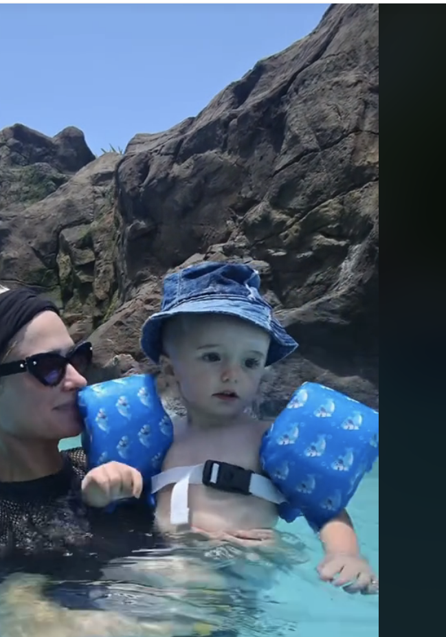 Paris Hilton is in a swimming pool holding a baby wearing arm floaties