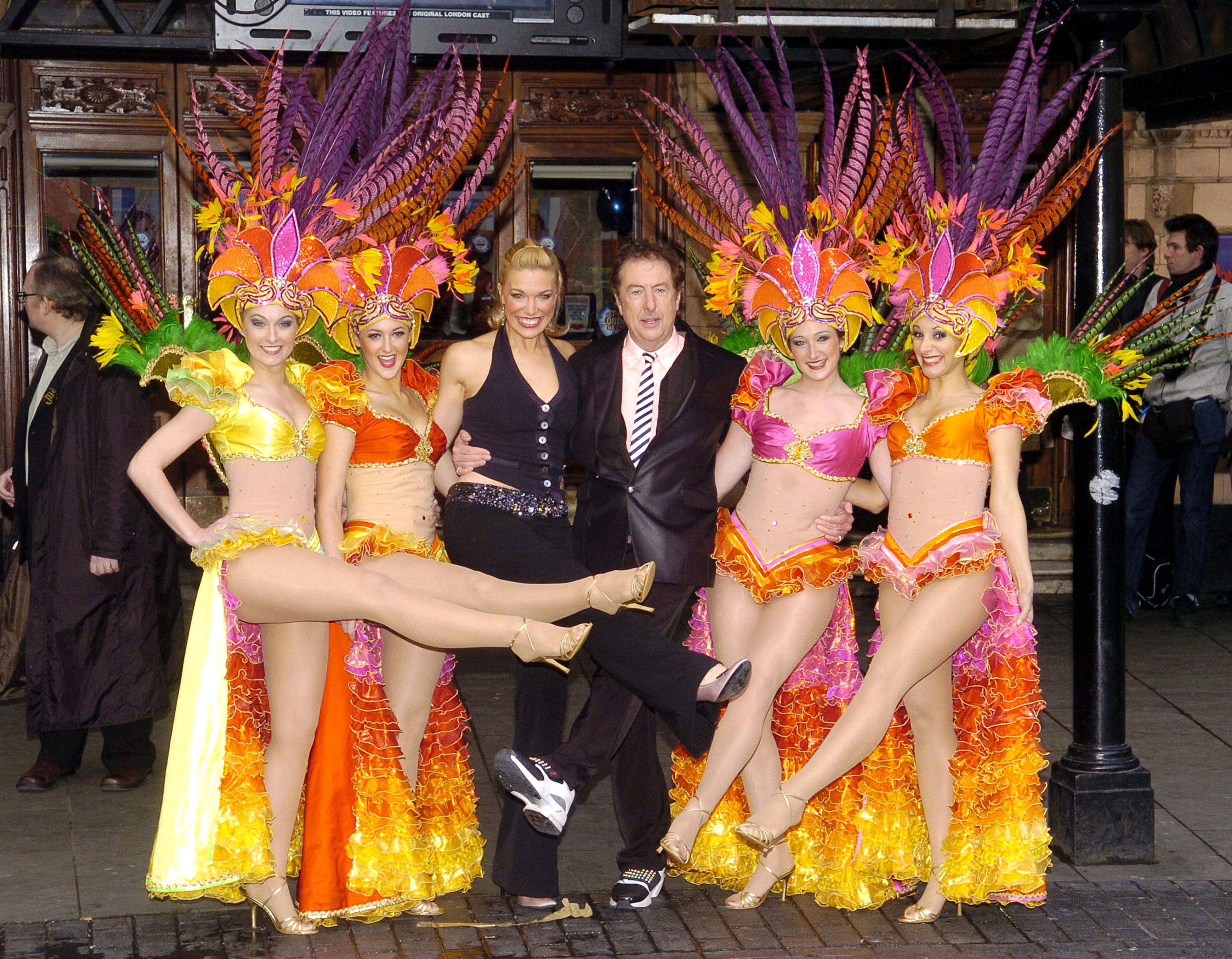 Hannah Waddingham posing with several people in elaborate costumes with feathered head pieces