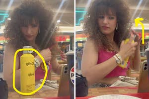 A woman with a curly hairstyle is using göt2b glued hairspray in a dining area. She is wearing a pink top and hoop earrings